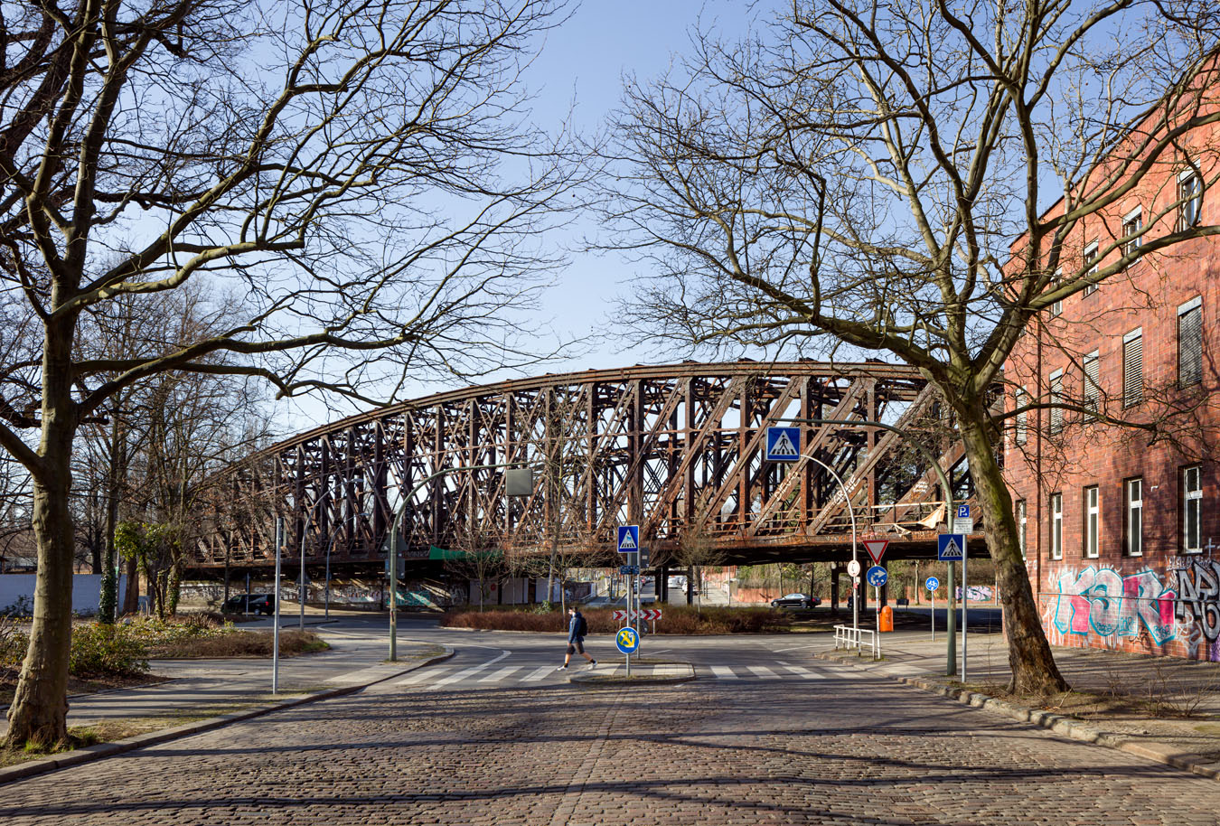 Totale der beiden Brücken. Im Vordergrund die Straße aus Kopfsteinpflaster und Zebrastreifen und im Hintergrund Autos.