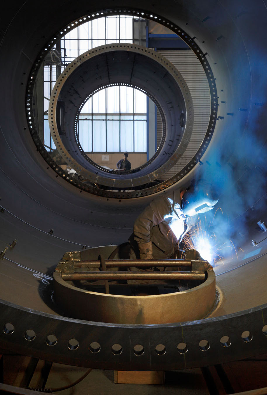 Industriefotografie in Brandenburg. Der Schweißer arbeitet am Stahlturm.